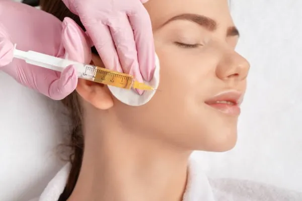 Prp injections near me; the profile face of a woman, while she is being injected