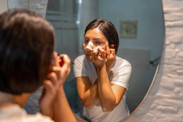 Rhinoplasty cost; a woman putting on makeup after her operation