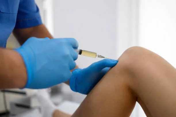 Medical professional applying PRP injection treatment on knee for inflammation.