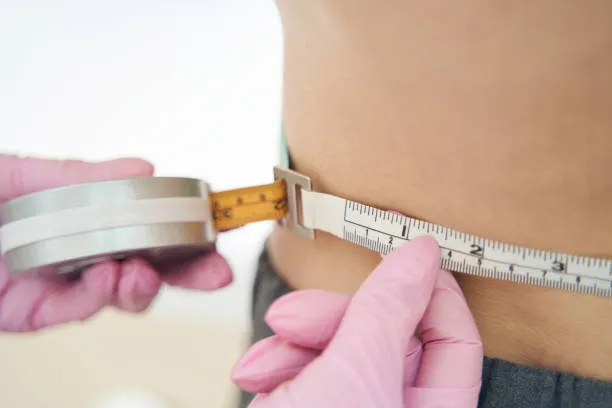 Plastic surgeon evaluating a patient’s treatment areas, explaining how the amount of unwanted fat may increase how much is liposuction.