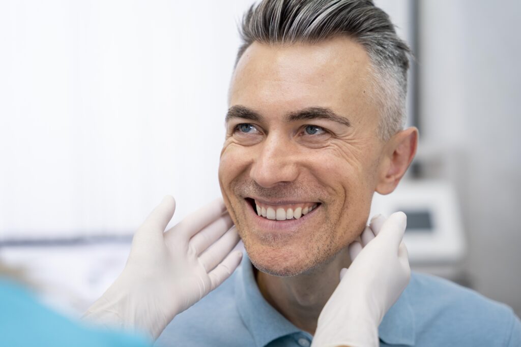 A dentist examining a patient's teeth to determine treatment options, explaining how much are dental implants based on individual needs
