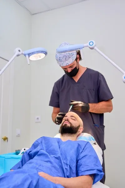 Surgeon performing FUE hair transplant on a patient in a clinical setting.