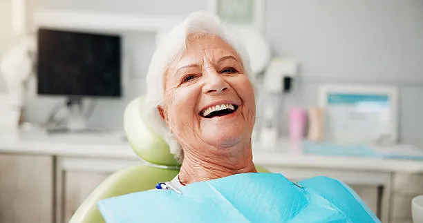 Senior woman smiling confidently after a dental implants treatment that restored her full set of teeth.