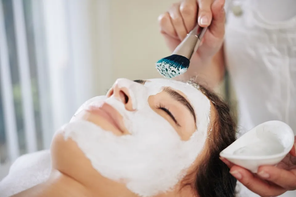 Close-up of a mask being applied to a client's face with a brush during facial treatments