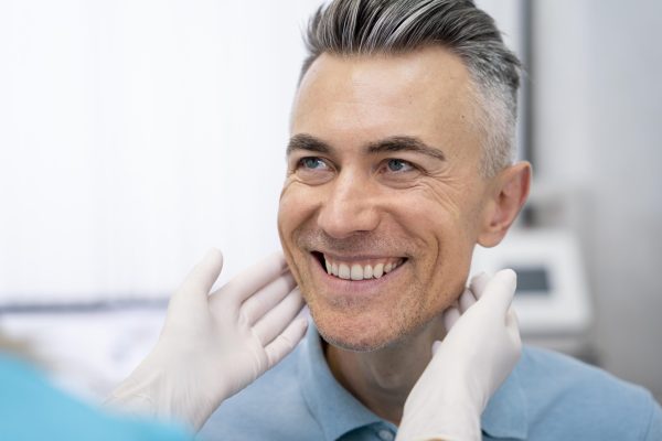 A dentist examining a patient's teeth to determine treatment options, explaining how much are dental implants based on individual needs